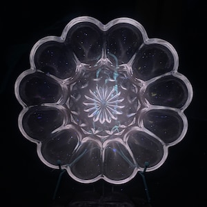 Peut inclure: Un plat de service en verre transparent avec un bord festonné et un motif décoratif au centre. Le plat est conçu pour contenir plusieurs petits articles, tels que des collations ou des amuse-gueules.