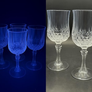 Peut inclure: Ensemble de verres à vin en cristal transparent. Les verres présentent un motif en losanges sur le bol et un pied fin. Les verres sont présentés sur une surface sombre, certains étant éclairés par une lumière bleue.