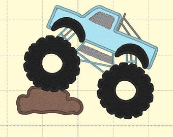 May include: An embroidery design featuring a light blue monster truck with large black tires, a grey window, and a grey roll cage. The truck is positioned at an angle, with one front tire resting on a brown, irregular-shaped patch of dirt.