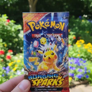 以下が含まれることがあります： ピカチュウのイラストが描かれた、未開封のポケモンカードパック。 パックは赤、青、黄色の配色で、「Pokémon Trading Card Game」と「Scarlet & Violet Surging Sparks」の文字が書かれています。 追加のゲームカードが10枚入っています。