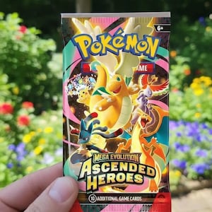 Peut inclure: Un paquet de cartes Pokémon Mega Evolution Ascended Heroes. Le paquet présente un design coloré avec divers personnages Pokémon, dont un grand dragon orange. Les textes "Pokémon" et "Ascended Heroes" sont bien en évidence.