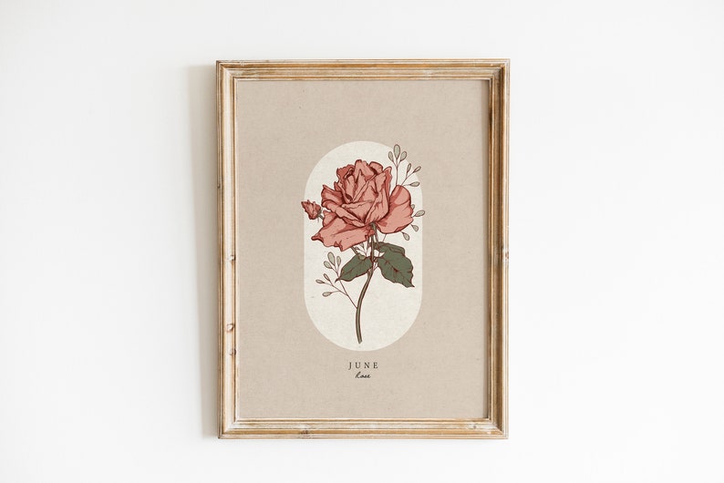 May include: A framed print with a beige background featuring a pink rose with green leaves and stems. The rose is surrounded by a light beige oval. The text "JUNE" and "Rose" is printed below the rose.
