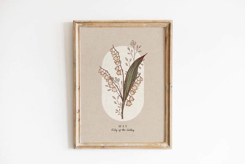 May include: Framed botanical print of Lily of the Valley. The artwork has a beige background with an oval shape, and the text "MAY" and "Lily of the Valley". The frame is a distressed, light brown colour.