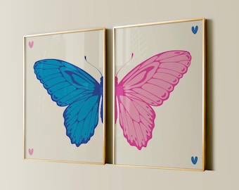 Pode incluir: Duas impressões emolduradas de borboletas, uma azul e outra rosa, com pequenos corações nos cantos de cada moldura.