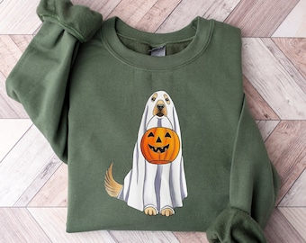 Puede incluir: Sudadera verde militar con un perro disfrazado de fantasma sosteniendo una calabaza. El perro lleva una sábana blanca con rayas grises y una calabaza naranja sonriente. Cuello redondo, mangas largas.