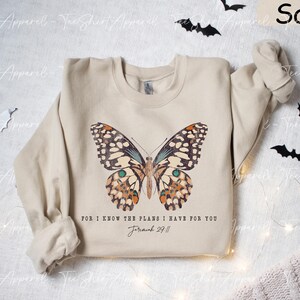May include: A beige sweatshirt with a butterfly graphic and the text "For I know the plans I have for you Jeremiah 29:11".