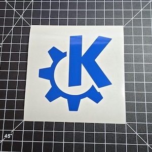May include: Blue vinyl decal with a stylized letter K inside a gear. The decal is on a white background.