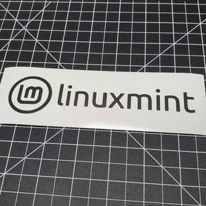 May include: A white sticker with a black Linux Mint logo. The logo features a stylized letter "m" inside a circle. The text "linuxmint" is to the right of the logo.
