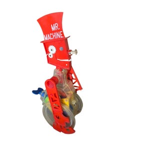 May include: A vintage Mr. Machine toy featuring a bright red plastic top hat with the text MR. MACHINE printed in white. The figure has a clear plastic torso revealing internal colorful gears and a blue winding key on the side of the body.