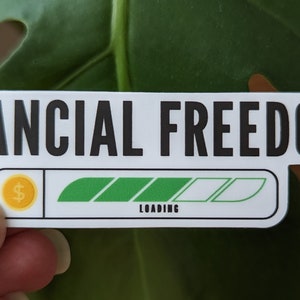 May include: White sticker with black text that reads "FINANCIAL FREEDOM" and a progress bar with a dollar sign icon. The progress bar is partially filled with green and white.