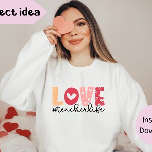 Pu&ograve; includere: Felpa bianca con una grafica rosa, rossa e arancione che dice "LOVE #teacherlife".
