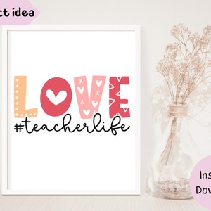 Pu&ograve; includere: Una stampa incorniciata bianca con la parola "LOVE" in lettere rosa e arancioni con cuori e il testo "#teacherlife" in scrittura corsiva nera.