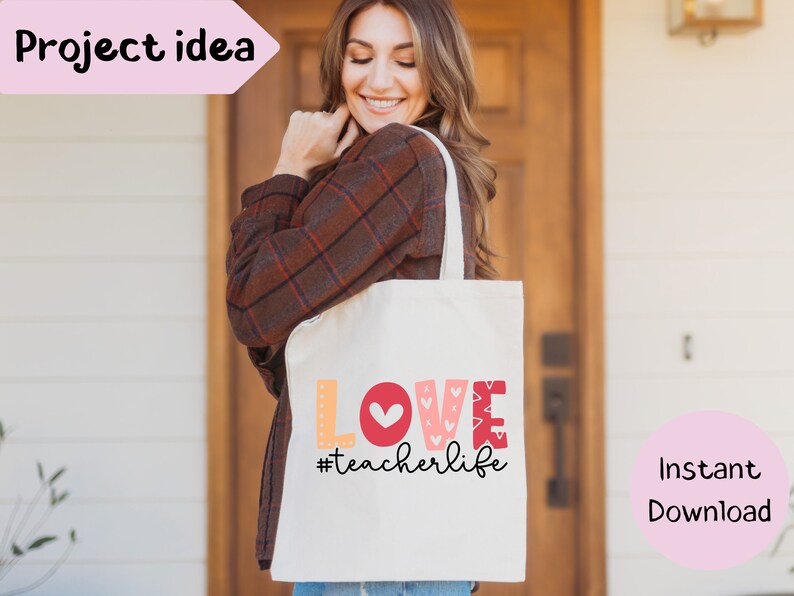 Pu&ograve; includere: Una borsa tote bianca con le parole "LOVE #teacherlife" in lettere colorate e un cuore rosso. La borsa &egrave; tenuta da una persona che indossa una camicia a quadri marroni.