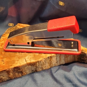 May include: A red and silver stapler with a black base. The stapler is labelled "Model 80".