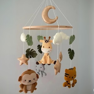 May include: A wooden baby mobile with a crescent moon, clouds, leaves, stars, and felt animal toys including a giraffe, monkey, and tiger.