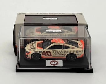 May include: A diecast model race car in a clear display case. The car is white with orange and black accents, and the number 40 is visible. The words "Traveller Whiskey" are printed on the side. The display case has a black base.