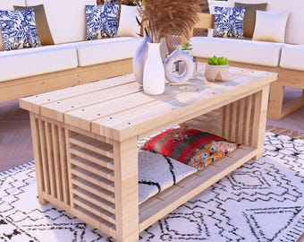 Puede incluir: Una mesa de centro de madera clara con un diseño lateral de listones y un estante inferior. La mesa está rodeada de sofás blancos con cojines estampados, una alfombra estampada y jarrones decorativos. La mesa mide aproximadamente 122 cm de largo, 61 cm de ancho y 46 cm de alto.