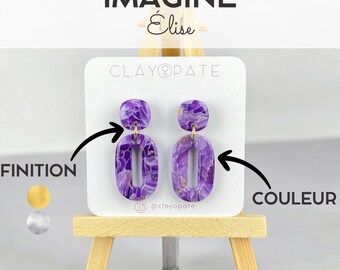 May include: A pair of purple and gold marbled oval drop earrings. The earrings are displayed on a white card with the text "CLAYOPATE" and "@clayopate". The word "IMAGINE" is at the top.