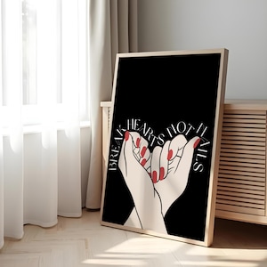 以下が含まれることがあります： 黒い背景に「Break Hearts Not Nails」の文字が入った額入りのアートプリント。赤いマニキュアを塗った2つの手が組み合わされています。フレームは明るい木の色です。