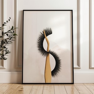 Op de afbeelding: Een ingelijste kunstdruk met een gestileerde afbeelding van een pincet die een set zwarte wimpers vasthoudt. De pincet is lichtbruin van kleur en de achtergrond heeft een zachte, neutrale tint.