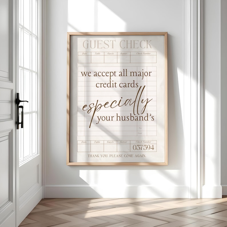 May include: A framed print with a light wood frame. The print is designed to look like a guest check, with the text "GUEST CHECK" at the top. The text reads "we accept all major credit cards, especially your husband's".
