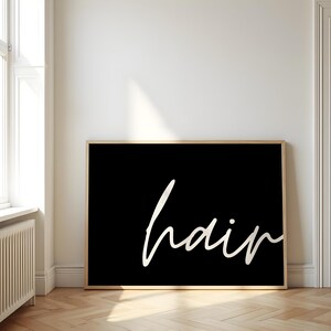Puede incluir: Una impresión enmarcada en blanco y negro con la palabra "hair" escrita en una fuente cursiva blanca.