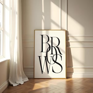 Op de afbeelding: Een zwart-witte poster met het woord "BROWS" geschreven in een gestileerd lettertype. De poster is ingelijst in een gouden lijst en hangt aan een witte muur.
