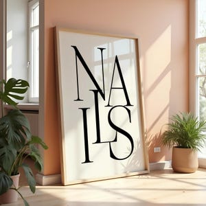 Peut inclure: Une affiche noire et blanche avec le mot "NAILS" imprimé dans une police de caractères stylisée. L'affiche est encadrée dans un cadre en bois clair et est accrochée à un mur.
