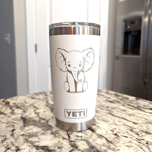 A white 20oz Yeti Rambler Tumbler laser etched with a sitting elephant. The tumbler is a play on a white elephant gift.