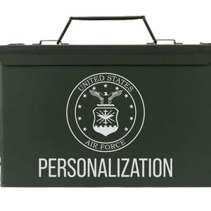 May include: A dark green metal box with a black handle and a white emblem of the United States Air Force. The text "PERSONALIZATION" is printed in white below the emblem. The box has a hinged lid and a latch.