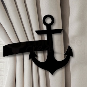 May include: A black anchor curtain tieback. The tieback is made of a solid material and features a nautical anchor design. The anchor is holding a section of light beige curtain.