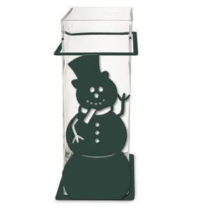 May include: A dark green metal vase with a snowman silhouette cutout. The vase is designed to hold a glass cylinder for flowers.