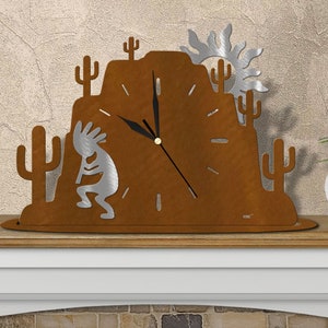 May include: A rustic metal clock featuring a desert scene with a stylized sun, cacti, and a Native American dancer. The clock face is brown with black hands and white numbers.