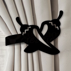 May include: Black metal curtain tieback shaped like two chili peppers. The tieback is designed to hold curtains in place, adding a decorative touch to window treatments. The peppers have a zig-zag design on the side.