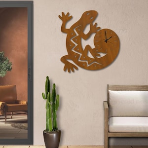 May include: A rust-colored metal wall clock shaped like a lizard. The lizard body features a cutout zigzag pattern with small circular holes. A circular clock face is integrated into the lizard's tail, featuring black hands and no numerals.