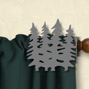 May include: A gray metal curtain finial shaped like a group of pine trees. The finial is attached to a wooden curtain rod with a brown finial.