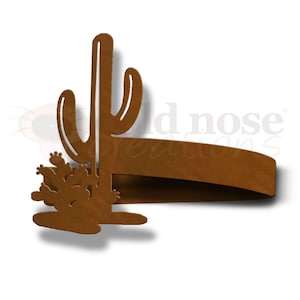 May include: A rustic brown metal napkin ring shaped like a cactus with a single tall cactus and a smaller cluster of cacti. The napkin ring is a decorative accent for a southwestern or desert themed table setting.