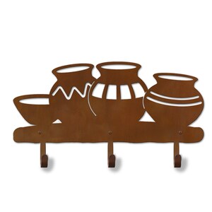 May include: Rustic brown metal key holder with three hooks shaped like stylized pottery. The key holder is mounted on a wooden shelf.