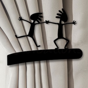 May include: Black metal curtain tiebacks shaped like stick figures holding hands. The tiebacks are mounted on a black metal rod.