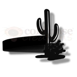May include: Black metal silhouette of a cactus with a single tall cactus and smaller cacti at the base. The silhouette is mounted on a black metal base.