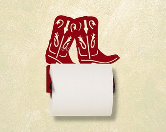 May include: Red metal cowboy boot toilet paper holder. The holder is shaped like two cowboy boots with white stitching detail. The toilet paper roll is white.
