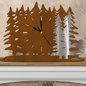May include: A rustic metal wall clock featuring a forest scene. The clock has a brown finish with a silver tree accent. The clock hands are black, and the clock is displayed on a wooden shelf.