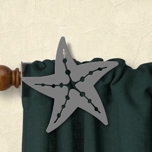 May include: A gray metal starfish curtain rod finial with a wooden finial on a dark green curtain.