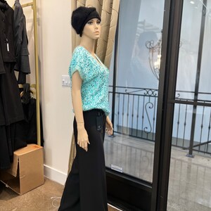 K&ouml;nnte beinhalten: Eine Schaufensterpuppe tr&auml;gt einen schwarzen Hut, ein hellblaues Oberteil mit Pailletten und eine schwarze weite Hose.