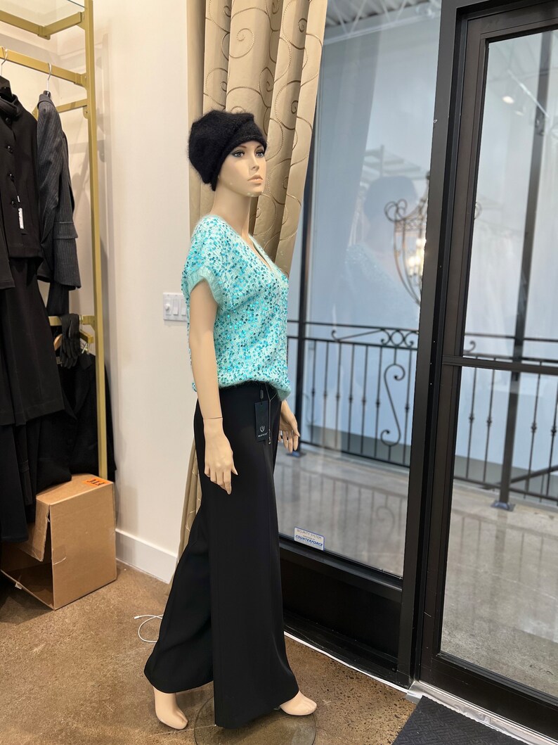 K&ouml;nnte beinhalten: Eine Schaufensterpuppe tr&auml;gt einen schwarzen Hut, ein hellblaues Oberteil mit Pailletten und eine schwarze weite Hose.