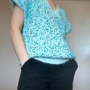 K&ouml;nnte beinhalten: Ein hellblauer Pailettenpullover mit V-Ausschnitt und kurzen &Auml;rmeln.