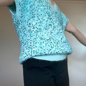 K&ouml;nnte beinhalten: Ein hellblauer Pailettenpullover mit kurzen &Auml;rmeln und V-Ausschnitt.