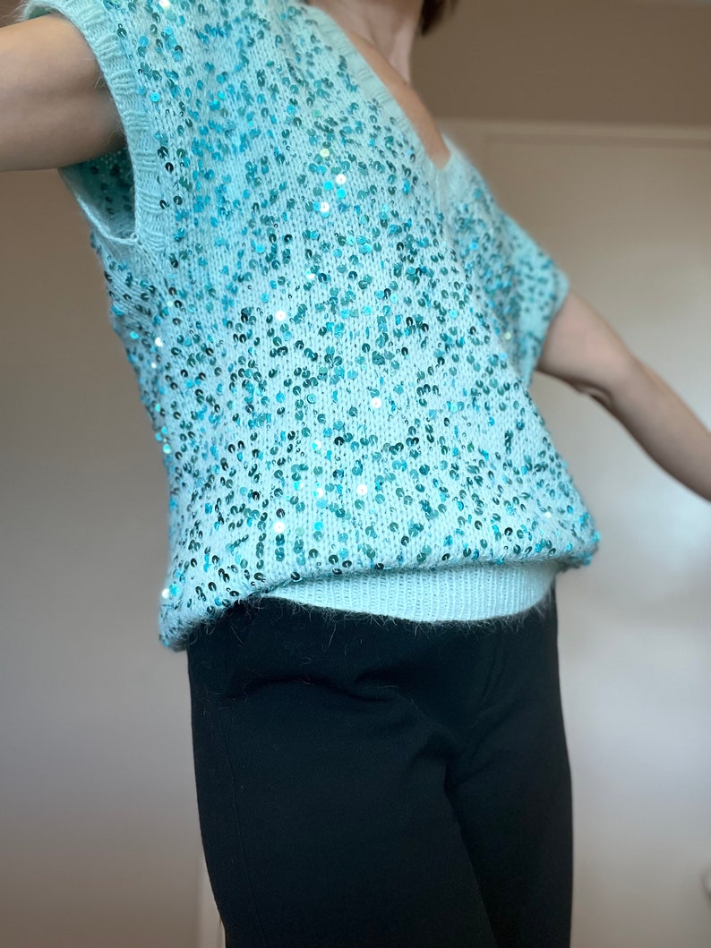 K&ouml;nnte beinhalten: Ein hellblauer Pailettenpullover mit kurzen &Auml;rmeln und V-Ausschnitt.