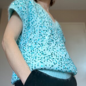 K&ouml;nnte beinhalten: Ein hellblauer Pailettenpullover mit V-Ausschnitt und kurzen &Auml;rmeln.