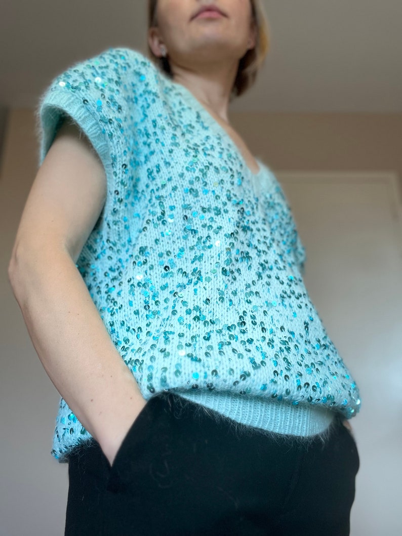 K&ouml;nnte beinhalten: Ein hellblauer Pailettenpullover mit V-Ausschnitt und kurzen &Auml;rmeln.